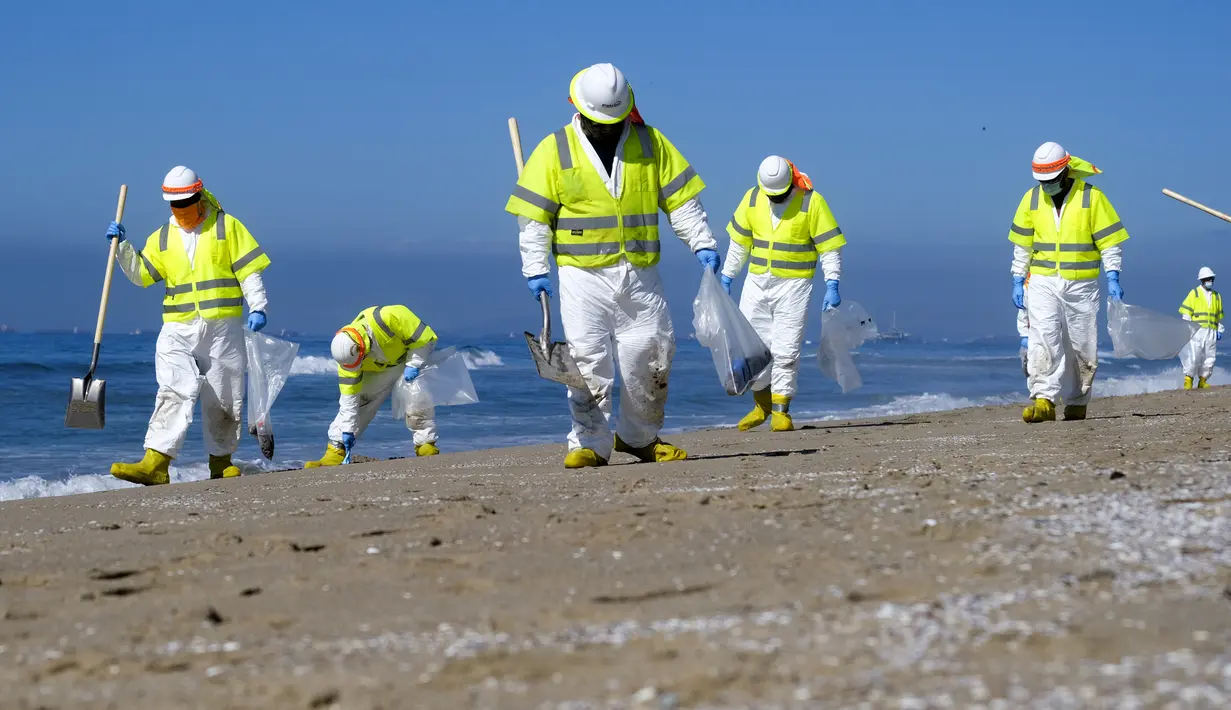 Pekerja dengan pakaian pelindung membersihkan pantai yang terkontaminasi tumpahan minyak di Huntington Beach, California, Amerika Serikat, Selasa (5/10/2021). Kebocoran pipa menyebabkan tumpahan minyak di lepas pantai California. (AP Photo/Ringo H.W. Chiu)