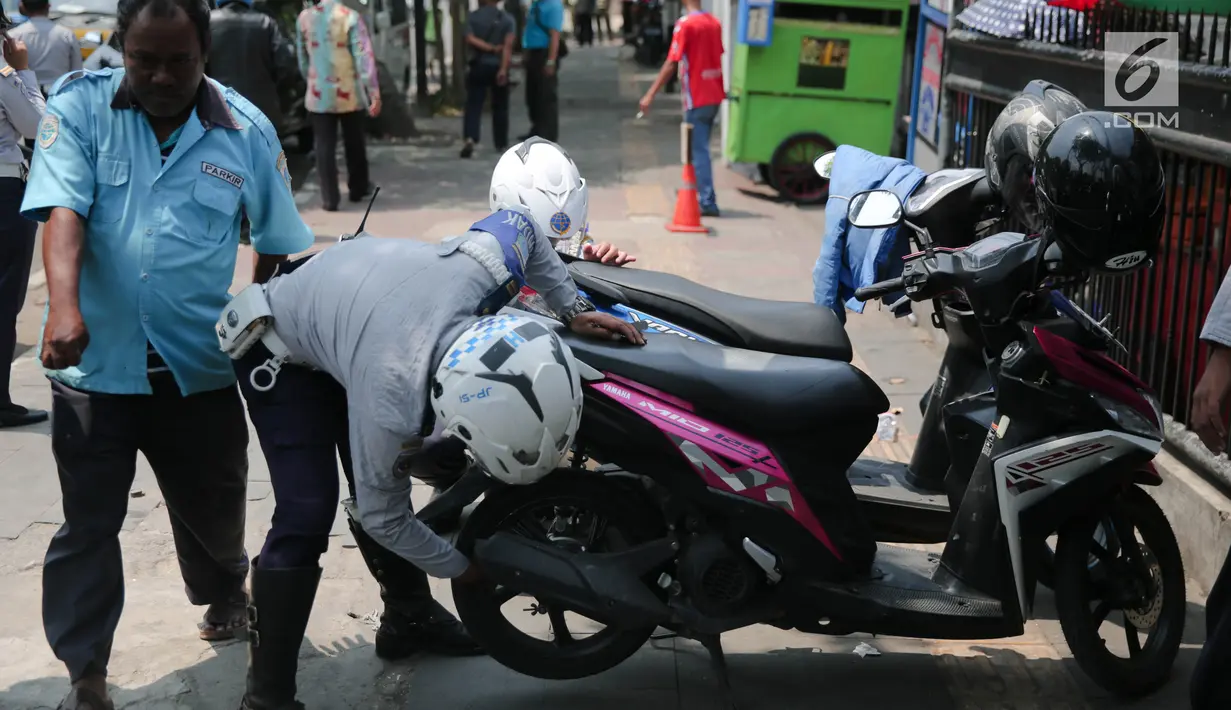 Petugas Dishub DKI menggembosi ban motor yang nekat parkir liar di trotoar sepanjang Jalan Kramat Raya, Senen, Jakarta, Jumat (22/9). Razia dilakukan untuk mengantisipasi arus lalu lintas yang kerap macet di kawasan itu. (Liputan6.com/Faizal Fanani)