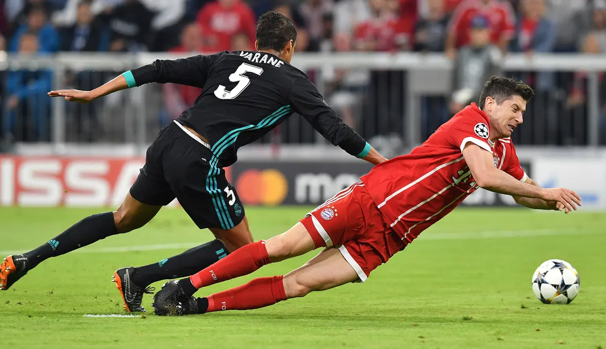 Pemain Bayern Munchen, Robert Lewandowski berebut bola dengan pemain Real Madrid, Raphael Varene pada leg pertama semifinal Liga Champions di Allianz Arena, Rabu (25/4). Real Madrid berhasil menumbangkan Bayern Munchen 2-1. (AP/Matthias Schrader)