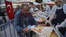 Orang-orang antre untuk mengambil makan berbuka puasa di Diyarbakir, Turki, Rabu (16/5). (ILYAS AKENGIN/AFP)