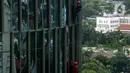 Pekerja saat membersihkan kaca gedung bertingkat di kawasan Kuningan, Jakarta, Minggu (19/12/2021). Pekerja ini harus bergelantungan dengan seutas tali untuk membersihkan dinding-dinding gedung bertingkat yang tingginya kurang lebih mencapai 150 meter. (Liputan6.com/Johan Tallo)