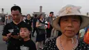 Warga berjalan menghadiri upacara pengibaran bendera saat fajar setelah kematian mantan perdana menteri China Li Peng di Lapangan Tiananmen Beijing (24/7/2019). Li Peng meninggal dunia akibat menderita kanker kandung kemih. (AFP Photo/Greg Baker)