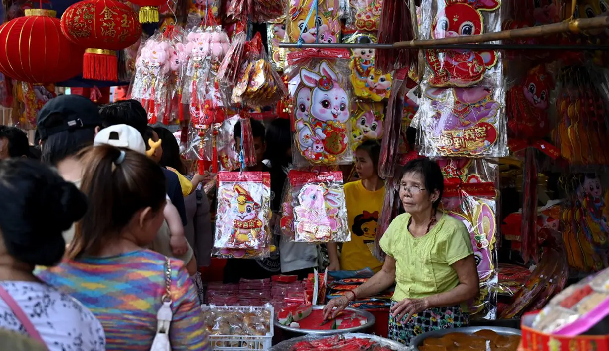 Pelanggan melihat dekorasi di kios pasar jalanan jelang Tahun Baru Imlek di Distrik Pecinan Yangon, Myanmar, 18 Januari 2023. Tahun Baru Imlek 2023 yang disebut sebagai Tahun Kelinci akan jatuh pada tanggal 22 Januari. (STRINGER/AFP)