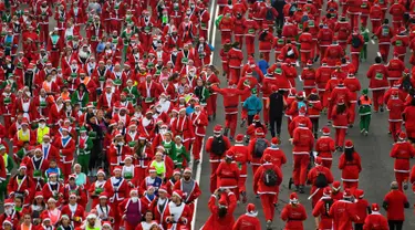 Orang-orang mengenakan kostum Sinterklas ambil bagian dalam Santa Claus Run di Madrid, Spanyol, Minggu (9/12). Ribuan orang berjalan dan berlari dalam perlombaan Santa tahunan melintasi jalan-jalan ibu kota Spanyol. (Gabriel BOUYS / AFP)