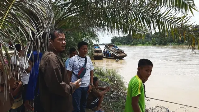 Warga melihat pencarian bocah lima tahun yang diseret buaya ke sungai di Riau.