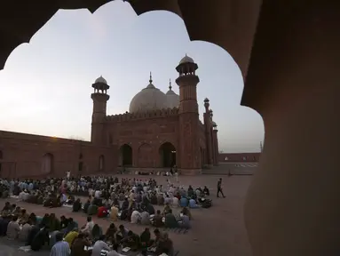 Orang-orang berbuka puasa selama bulan suci Ramadhan di masjid bersejarah Badshahi, di Lahore, Pakistan (3/4/2022). Ramadhan ditandai dengan puasa setiap hari dari fajar hingga matahari terbenam. (AP Photo/K.M. Chaudary)