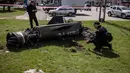 Polisi Ukraina memeriksa sisa-sisa roket besar dengan tulisan "untuk anak-anak kita" dalam bahasa Rusia di sebelah bangunan utama stasiun kereta api yang digunakan untuk evakuasi warga sipil, yang terkena serangan roket di Kramatorsk, Ukraina timur (8/4/2022). (AFP/Fadel Senna)