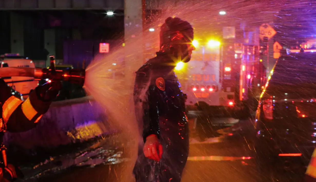 Seorang penyelam FDNY disemprot air setelah mengevakuasi korban jatuhnya helikopter di East River di New York City, AS (11/3). Heli itu sempat terjungkal sebelum akhirnya masuk ke dalam air. (Eduardo Munoz Alvarez/Getty Images North America/AFP)