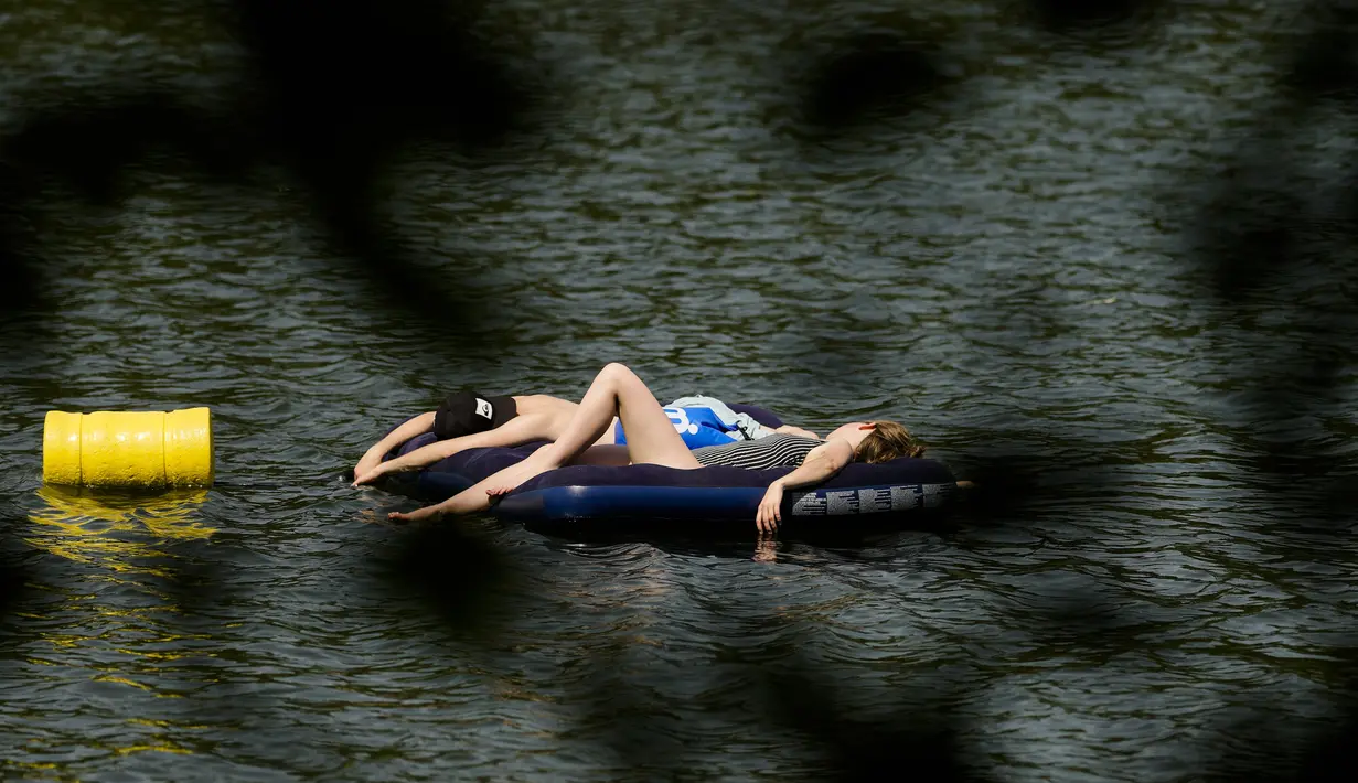 Orang-orang beristirahat di kasur udara pada hari musim panas di danau Orankesee di Berlin, Jerman, Minggu (19/6/2022). Di Jerman, di mana suhu tertinggi diperkirakan 38 derajat celcius (100,4 F), menteri kesehatan mendesak kelompok rentan menjaga tubuh tetap terhidrasi. (AP Photo/Markus Schreiber)