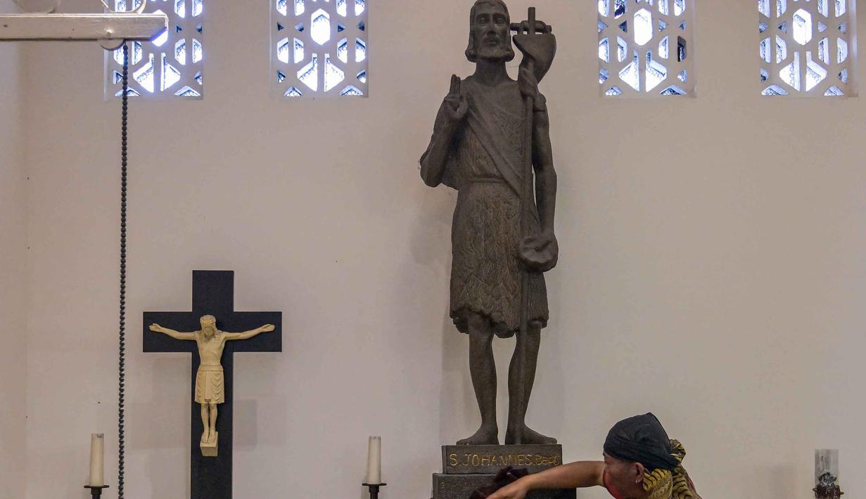 Kegiatan ini bertujuan memperingati kelahiran Yesus Kristus. Tampak dalam foto, seorang pekerja membersihkan patung Santo Yohanes Pembaptis di Katedral Hati Kudus Yesus, yang dikenal secara lokal sebagai gereja "Hati Kudus Yesus", selama persiapan Misa Natal di Surabaya, Jawa Timur, pada Selasa 23 Desember 2025. (JUNI KRISWANTO/AFP)
