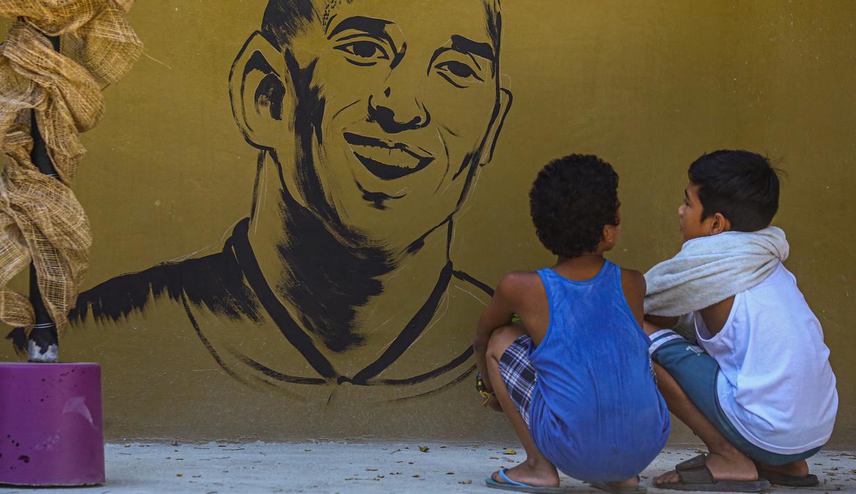 Anak-anak memandangi mural Kobe Bryant yang terletak di Manila, Filipina, Senin (27/1). Akibat kecelakaan helikopter, legenda NBA itu wafat bersama sang putri. (AFP/Maria Tan)