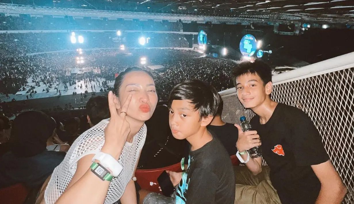 Hesti Purwadinata menonton konser Coldplay Jakarta bersama keluarganya. Ia mengenakan tank top hitam ditumpuk atasan jaring berwarna putih. Makeupnya natural yang memperlihatkan kecantikan kulitnya. [Foto: Instagram/hestipurwadinata]