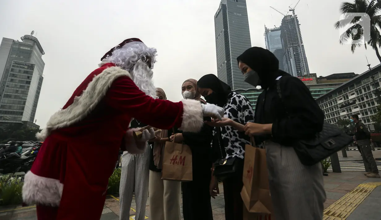 Seorang berpakaian sinterklas membagikan hadiah kepada warga saat acara Christmas in Jakarta di Bundaran Hotel Indonesia, Jakarta, Selasa (21/12/2021). Pemerintah Provinsi DKI Jakarta menggelar Christmas in Jakarta dalam rangka menyambut Natal 2021. (Liputan6.com/Johan Tallo)