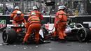 Sejumlah marshall berusaha mengevakuasi mobil pembalap Haas, Mick Schumacher usai mengalami kecelakaan saat Formula 1 GP Monako yang berlangsung di Circuit de Monaco, Minggu, 29 Mei 2022. (AFP/Loic Venance)