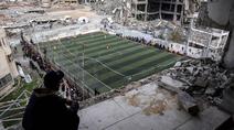 Warga Palestina menyaksikan pertandingan sepak bola lima lawan lima di tengah reruntuhan bangunan yang hancur di Kota Gaza pada Senin 9 Februari 2026. Keriuhan memecah kesunyian di antara reruntuhan bangunan di Kota Gaza. (Omar AL-QATTAA/AFP)