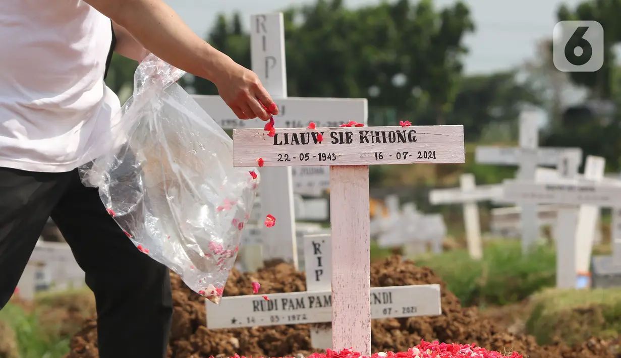 Umat katolik menabur bunga di atas makam saat  misa peryaan ekaristi peringatan arwah bagi korban Covid-19 di area TPU Rorotan, Jakarta Utara, Selasa (30/11/2021). Perayaan misa tersebut digelar di area pemakaman khusus Covid-19 TPU Rorotan (Liputan6.com/Herman Zakharia)