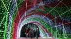 Pengunjung berjalan melalui terowongan cahaya pada pertunjukan cahaya Holiday Road di Calabasas, California, Amerika Serikat, 10 Desember 2021. Holiday Road digelar sepenuhnya setelah pandemi COVID-19 mengubah festival cahaya tahunan ini menjadi acara drive-thru tahun lalu. (AP Photo/Jae C.Hong)