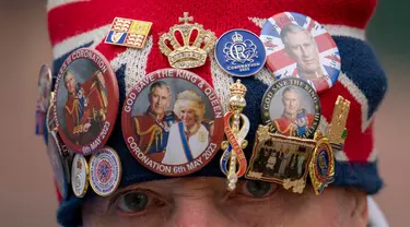 John Loughrey mengenakan topi yang dihiasi dengan memorabilia kerajaan sambil berdiri di sepanjang rute Penobatan Raja di The Mall di London, Selasa, 2 Mei 2023. (AP Photo/Vadim Ghirda)