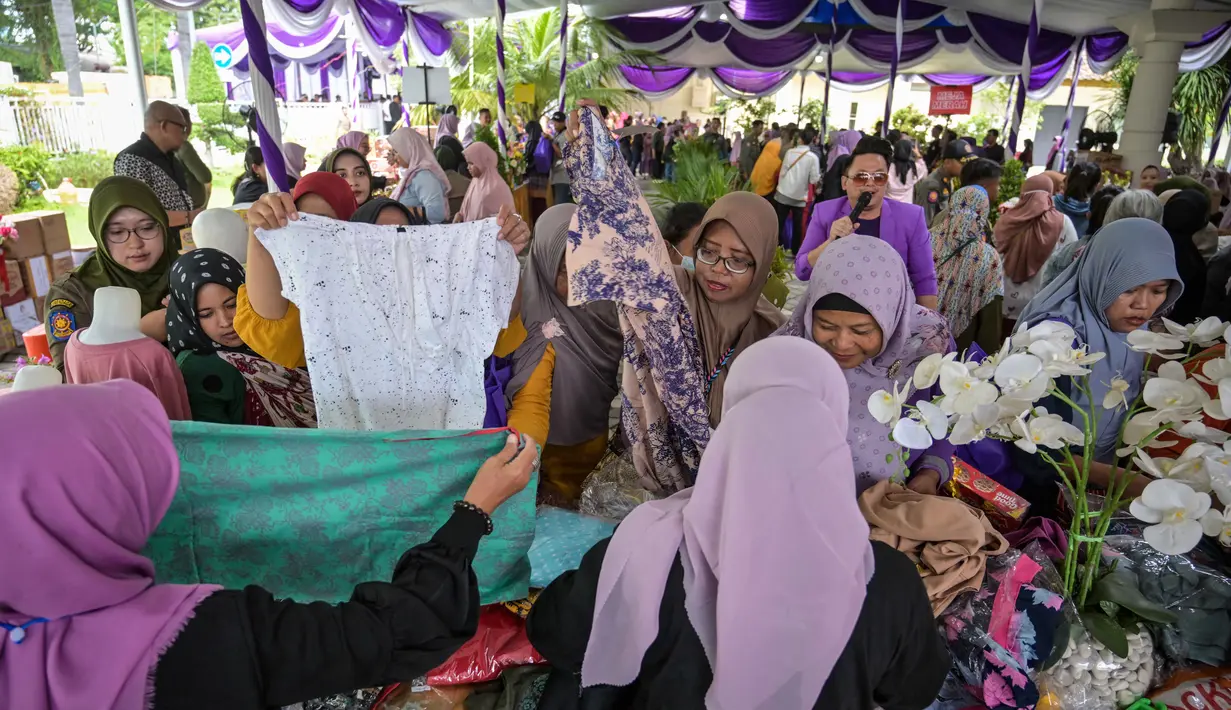 Masyarakat menerima barang-barang gratis seperti pakaian, bahan makanan pokok, dan perlengkapan rumah tangga yang disediakan oleh Asosiasi Organisasi Wanita (GOW) dan pemerintah daerah selama kegiatan aksi sosial tahunan di bulan Ramadan, Surabaya pada Senin 2 Maret 2026. (JUNI KRISWANTO/AFP)