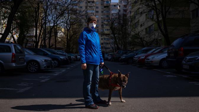 Alexandra Robu (34) berpose dengan anjingnya Dante (12) di Bucharest (29/3/2020). Undang-undang militer, yang disahkan pemerintah Rumania untuk mengurangi penyebaran virus corona, menyatakan berjalan bersama anjing adalah salah satu  kegiatan yang masih diizinkan. (AFP/Andrei Pungovschi)