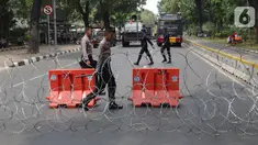 Personel Kepolisian melintas dibalik barikade kawat berduri yang menutup ruas Jalan Medan Merdeka Barat, Jakarta, Senin (28/10/2019). Penutupan ini antisipasi aksi unjuk rasa mahasiswa mendesak Presiden Jokowi segera mengeluarkan Perppu KPK. (Liputan6.com/Helmi Fithriansyah)