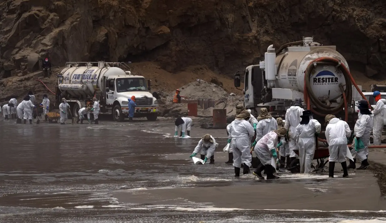 Petugas kebersihan bekerja untuk mengeluarkan minyak dari Pantai Cavero di Callao, Peru, 26 Januari 2022. Pembersihan Pantai Cavero dari tumpahan minyak kapal tanker Mare Doricum yang dihantam gelombang akibat letusan gunung berapi Tonga masih terus dilakukan. (Cris BOURONCLE/AFP)