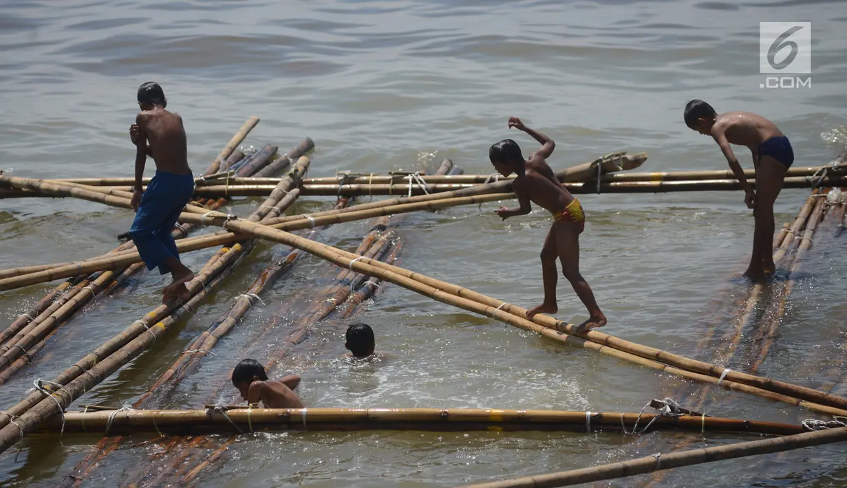 Dua anak berjalan di atas batang kayu bekas dermaga sandar kapal tradisional di Kawasan Cilincing, Jakarta, Selasa (10/4). (Merdeka.com/Imam Buhori)