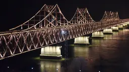 Suasana  Jembatan Persahabatan saat malam terlihat dari kota Dandong di provinsi Liaoning, China (22/2). Pemimpin Korut Kim Jong Un diperkirakan akan melintasi jembatan ini untuk melakukan pertemuan dengan Presiden AS Donald Trump. (AFP Photo/Greg Baker)