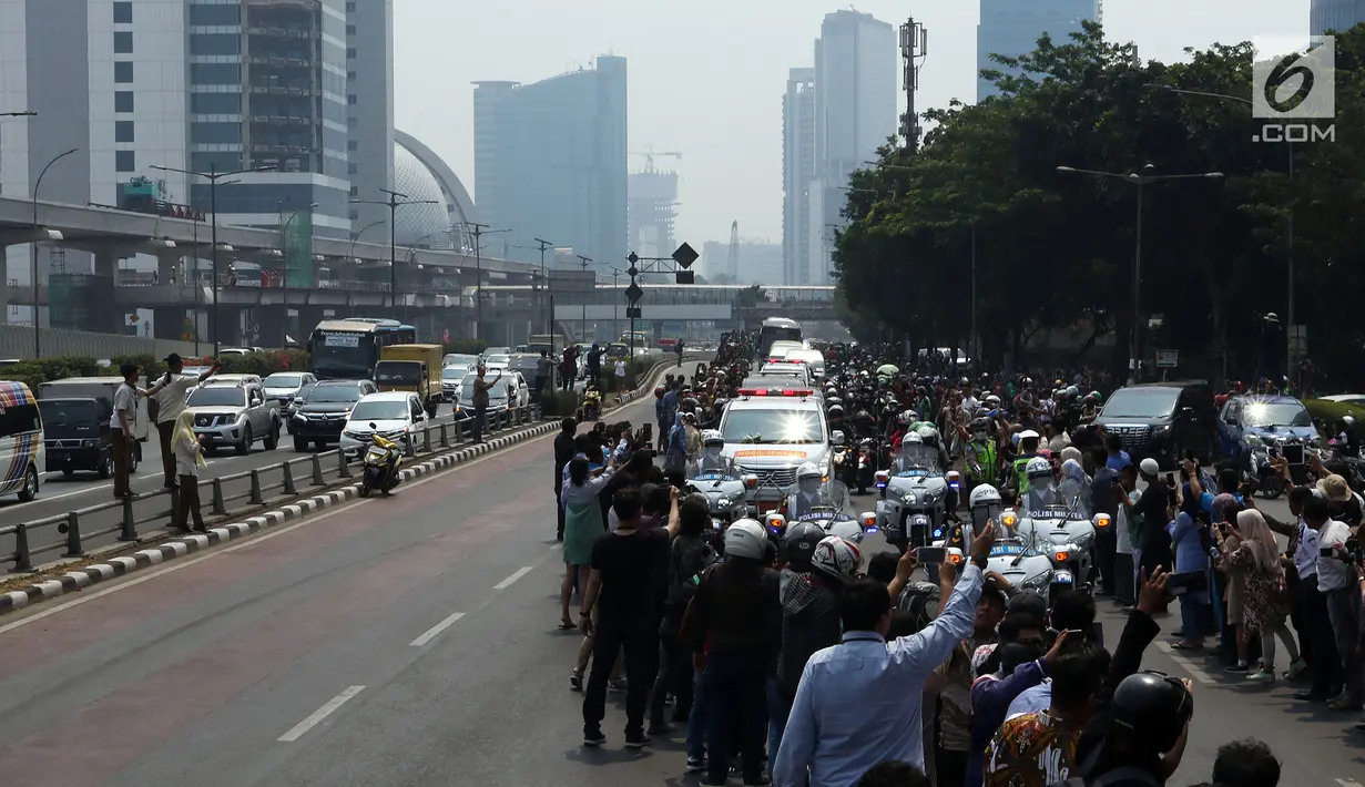 Warga mengambil gambar iring-iringan mobil jenazah yang membawa almarhum Presiden ke-3 RI, BJ Habibie saat melintasi Jalan Gatot Subroto menuju TMP Kalibata, Jakarta, Kamis (12/9/2019). BJ Habibie meninggal pada Rabu (11/9/2019) setelah menjalani perawatan di RSPAD. (Liputan6.com/Johan Tallo)