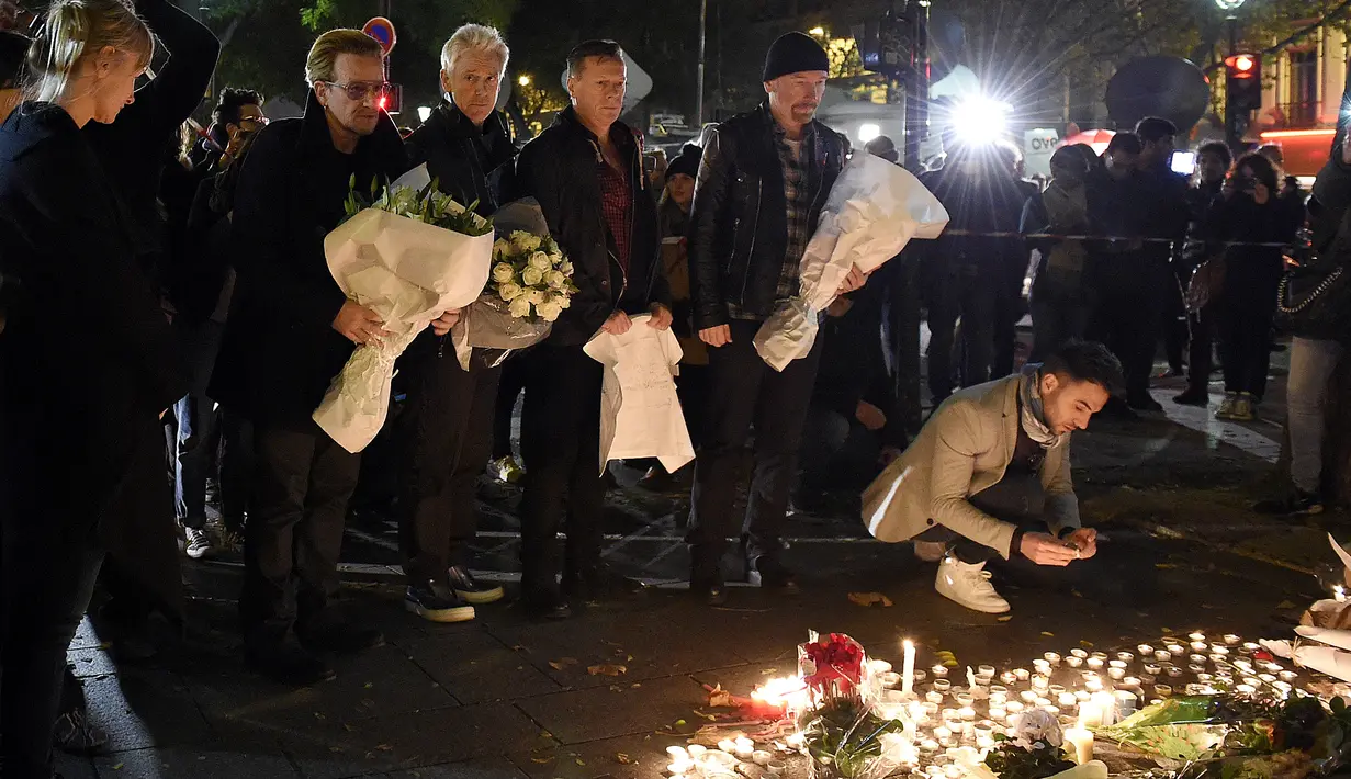 Grup band U2 Bono, Adam Clayton , Larry Mullen Jr  dan The Edge meletakkan karangan bunga di trotoar di depan gedung pertunjukan Bataclan Theatre, salah satu tempat serangan teroris di Paris, Perancis, Sabtu (14/11). (AFP PHOTO / FRANCK FIFE)