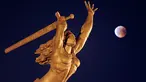 Fenomena gerhana bulan total "Micro Blood Moon" terlihat di dekat patung Dewi Kemenangan di Warsawa, Polandia, Jumat (27/7). Gerhana bulan yang terlama pada abad ini dapat disaksikan di seluruh dunia dengan mata telanjang. (AP/Alik Keplicz)