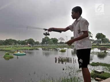 Seorang anak memancing di area banjir yang merendam TPU Semper, Jakarta, Selasa (4/12). TPU Semper menjadi langganan banjir saat musim penghujan akibat rendahnya permukaan tanah dengan ketinggian air sepinggang orang dewasa. (Merdeka.com/Iqbal S. Nugroho)