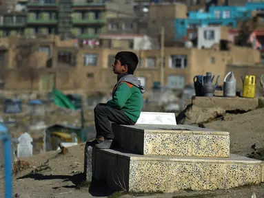 Afghan Zilgai (9), bocah penjual air ketika tengah menunggu pembeli di pemakaman Kart-e-Sakhi, Kabul, 20 Februari 2016. Anak sulung dari 8 bersaudara itu menjual air dari fajar hingga senja kepada para peziarah. (AFP PHOTO/Wakil KOHSAR)