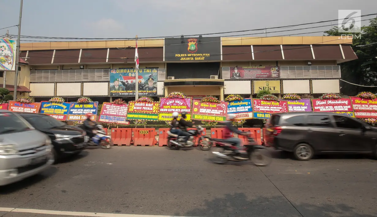 Kendaraan melintas di depan Polres Jakarta Barat yang dipenuhi karangan bunga, Jumat (23/11). Karangan bunga yang dikirimkan warga tersebut diberikan guna mendukung kepolisian dalam memberantas aksi premanisme di Jakbar. (Liputan6.com/Faizal Fanani)