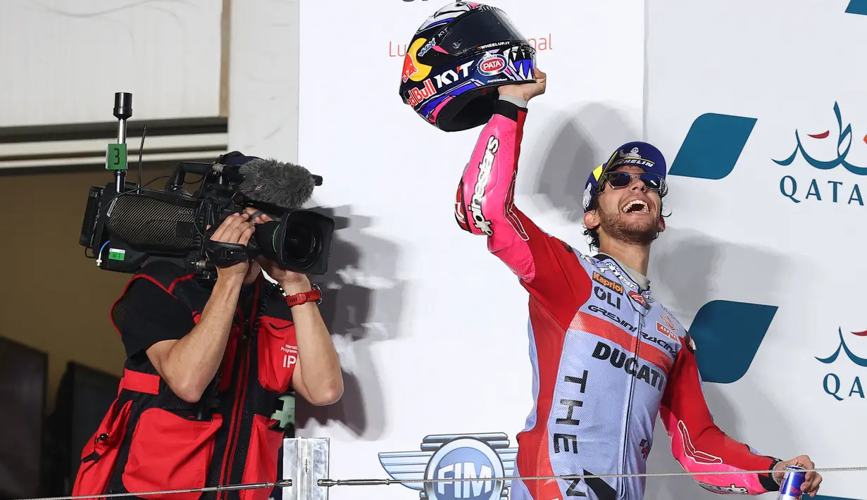 Pembalap tim Gresini Racing, Enea Bastianini berselebrasi di podium setelah memenangkan MotoGP Qatar di Sirkuit Internasional Lusail, Minggu (6/3/2022). Bastianini menyelesaikan balapan dengan waktu 42 menit 13,198 detik untuk merebut kemenangan perdana di kelas MotoGP. (KARIM JAAFAR/AFP)