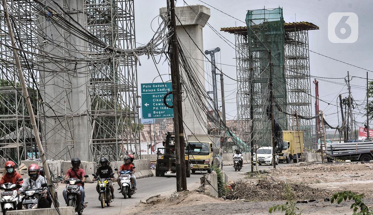 Kendaraan melintas dekat instalasi kabel yang semrawut di Jalan Raya Bekasi, Cakung, Jakarta, Rabu (30/9/2020). Minimnya perawatan pascapembebasan lahan permukiman untuk proyek Tol Dalam Kota membuat jaringan kabel listrik di sepanjang jalan tersebut semrawut. (merdeka.com/Iqbal S. Nugroho)