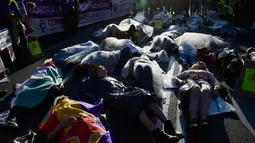 Sejumlah pengunjuk rasa berbaring dan membungkus diri dengan plastik saat melakukan aksi di Madrid, Spanyol (16/5). Dalam aksi tersebut mereka juga menuntut pemerintah agar meningkatkan daya ekonomi untuk wanita. (AFP/Javier Soriano)