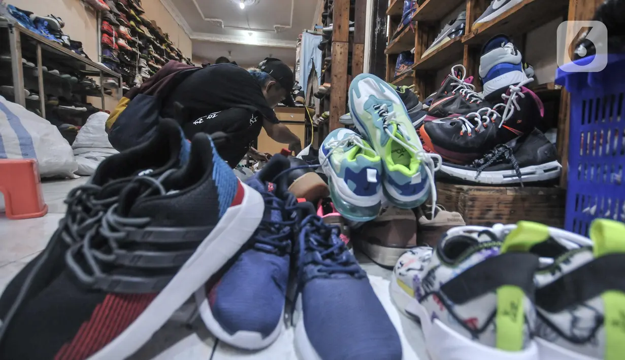 Calon pembeli saat melihat koleksi sepatu impor bekas di toko Second BJR, Kali Baru Timur, Cilincing, Jakarta Utara, Rabu (1/6/2022). Harga sepatu impor bekas mulai dijual oleh Bajuri kisaran Rp250 ribu hingga Rp7 juta per pasang. (merdeka.com/Iqbal S. Nugroho)