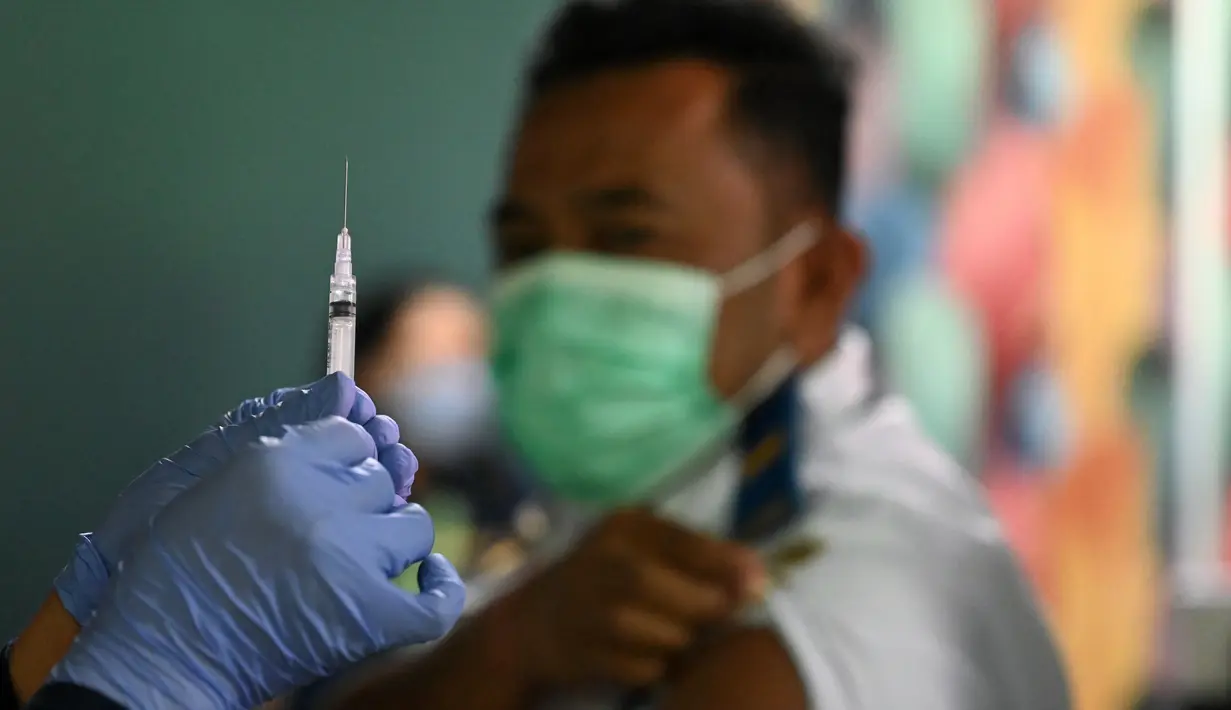 Seorang petugas kesehatan menyiapkan suntikan vaksinasi COVID-19 keempat atau booster kedua untuk petugas bandara di kantor otoritas Bandara Ngurah Rai, dekat Denpasar, Bali, Senin (30/1/2023). Para pekerja di bandara ini merupakan garda terdepan yang berinteraksi langsung dengan pelaku perjalanan luar negeri atau PPLN. (SONNY TUMBELAKA / AFP)