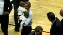 President Amerika Serikat Barack Obama menggendong anak-anak pada pembukaan NBA antara  Cleveland Cavaliers melawan Chicago Bulls di Chicago, Selasa(27/10/2015). (REUTERS / Jonathan Ernst)