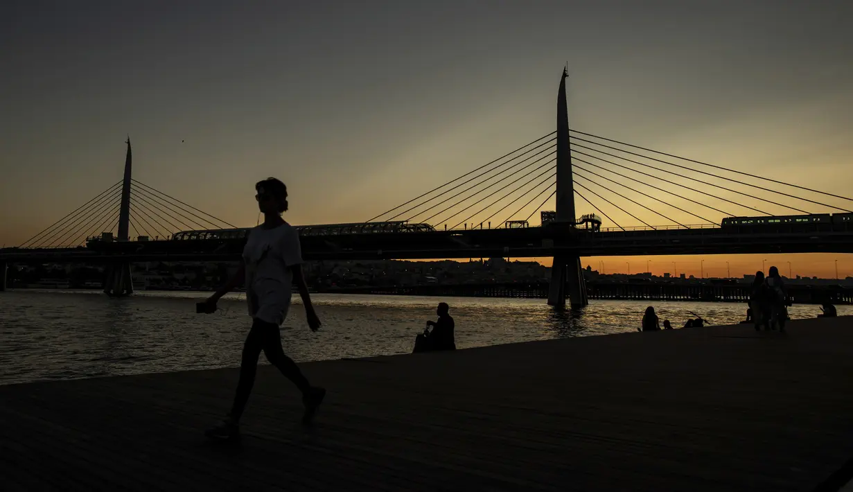 Seorang wanita berjalan di dekat the Golden Horn atau tanduk emas di Istanbul (26/7/2019). Tanduk Emas merupakan jalur air perkotaan utama dan pintu masuk utama Bosphorus di Istanbul, Turki. (AP Photo/Emrah Gurel)