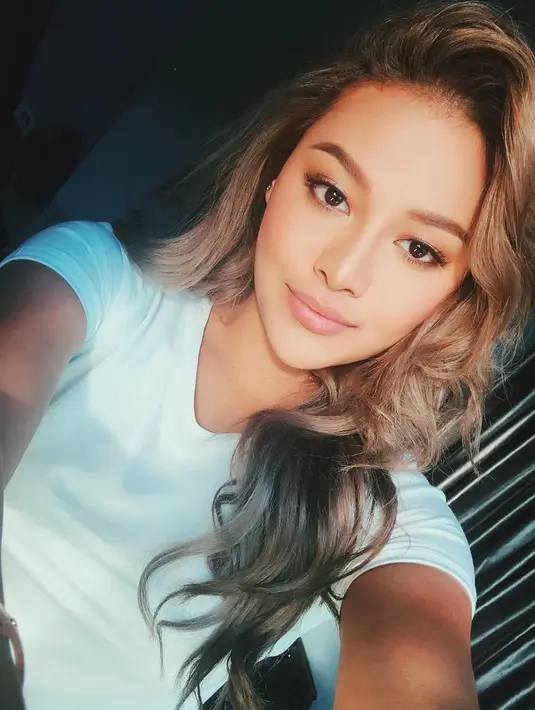 Saat di rumah saja, penampilan remaja kelahiran 1998 ini tetap cantik meski memakai kaos putih. Membiarkan rambut coklatnya tergerai, gaya simplenya tetap memesona. (Liputan6.com/IG/@aurelie.hermansyah)