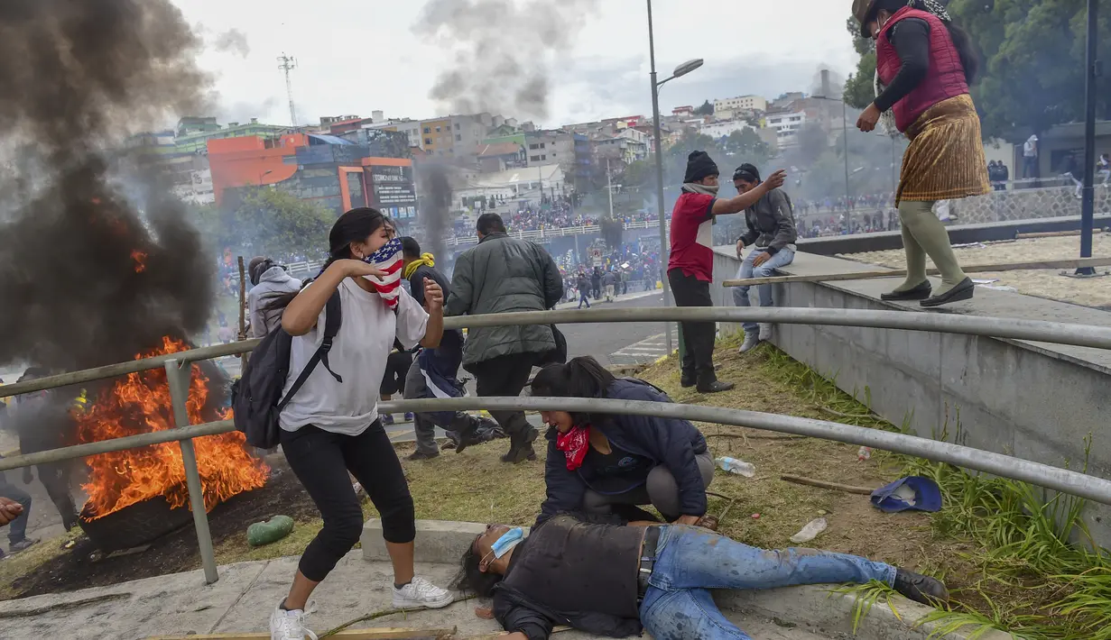 Seorang pengunjuk rasa terbaring di tanah ketika demonstran dibubarkan dari gedung parlemen oleh polisi anti huru hara  di Quito (8/10/2019). Para demonstran memprotes terhadap keputusan Presiden Ekuador Lenin Moreno yang mencabut subsidi bahan bakar. (AFP Photo/Martin Bernetti)