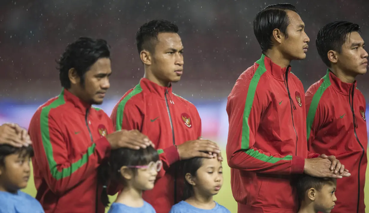 Bek Timnas Indonesia, Hansamu Yama, melindungi seorang anak dari hujan saat akan melawan Islandia pada laga persahabatan di SUGBK, Jakarta, Minggu (14/1/2018). Timnas Indonesia kalah 1-4 dari Islandia. (Bola.com/Vitalis Yogi Trisna)