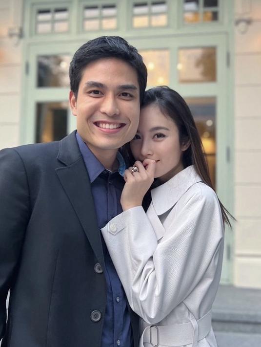 Nong Poy memamerkan cincin saat bersama calon suaminya. Dalam foto tersebut, ia mengenakan coat abu-abu dengan riasan wajah minimalis bahkan terlihat tanpa makeup. @poydtreechada.