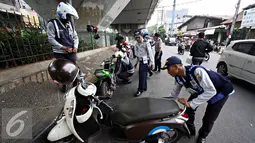 Petugas Dishub mencabut pentil kendaraan roda dua dalam operasi penertiban parkir liar di Pusat, Jumat (23/10/2015). Meskipun informasi penertiban diduga telah bocor, ratusan kendaraan yang parkir liar tetap ditertibkan. (Liputan6.com/Immanuel Antonius)