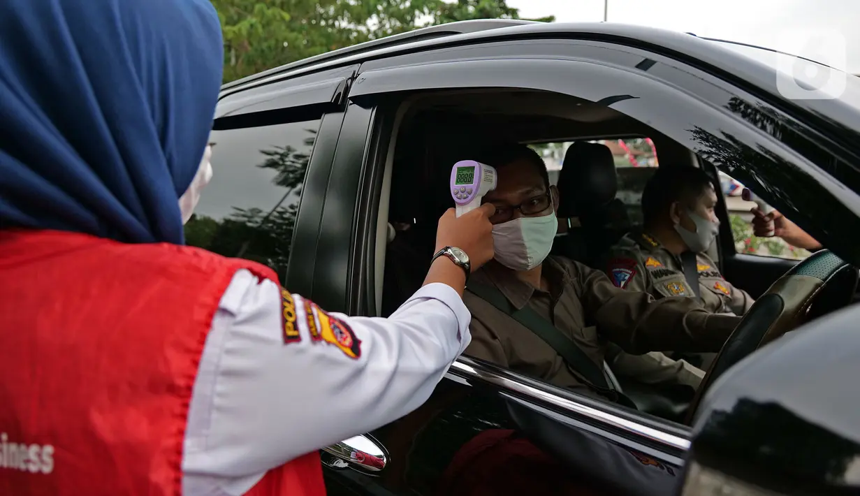 Petugas mengecek suhu tubuh saat di rest area KM 62 tol Jakarta Cikampek, Jawa Barat, Kamis (28/5/2020). Larangan mudik Idul Fitri 1441 H dan ketatnya keluar masuk kendaraan di sejumlah daerah berimbas pada penurunan pendapatan para penjual di rest area tersebut. (Liputan6.com/Herman Zakharia)
