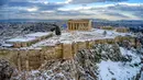 Bukit Acropolis kuno tertutup salju setelah hujan salju lebat di Athena, Yunani, Rabu (17/2/2021). Salju biasanya hanya turun di pegunungan Yunani dan di bagian utara negara itu. (Antonis Nikolopoulos/Eurokinissi via AP)