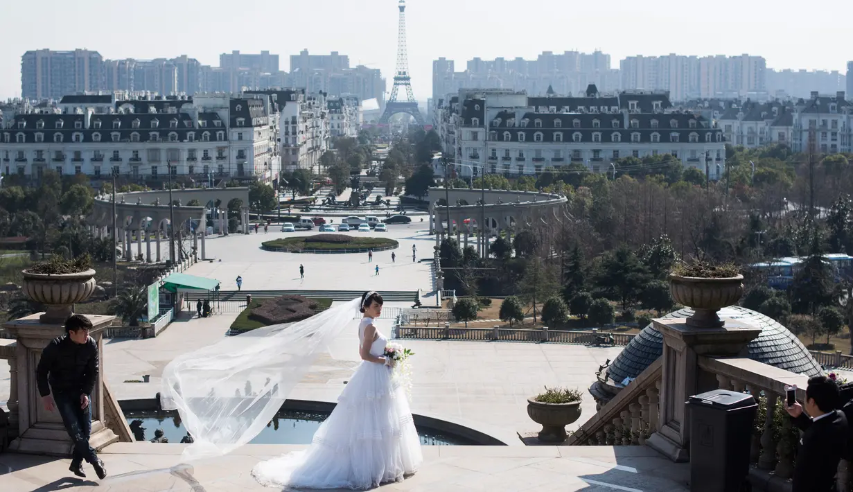 Calon pengantin berpose di dekat replika Menara Eiffel di Tianducheng, pinggiran Hangzhou, China, 26 Januari 2016. Kota Paris buatan yang didirikan di atas lahan 19 km persegi ini membutuhkan waktu 5 tahun dalam pembangunannya. (AFP PHOTO/Johannes EISELE)