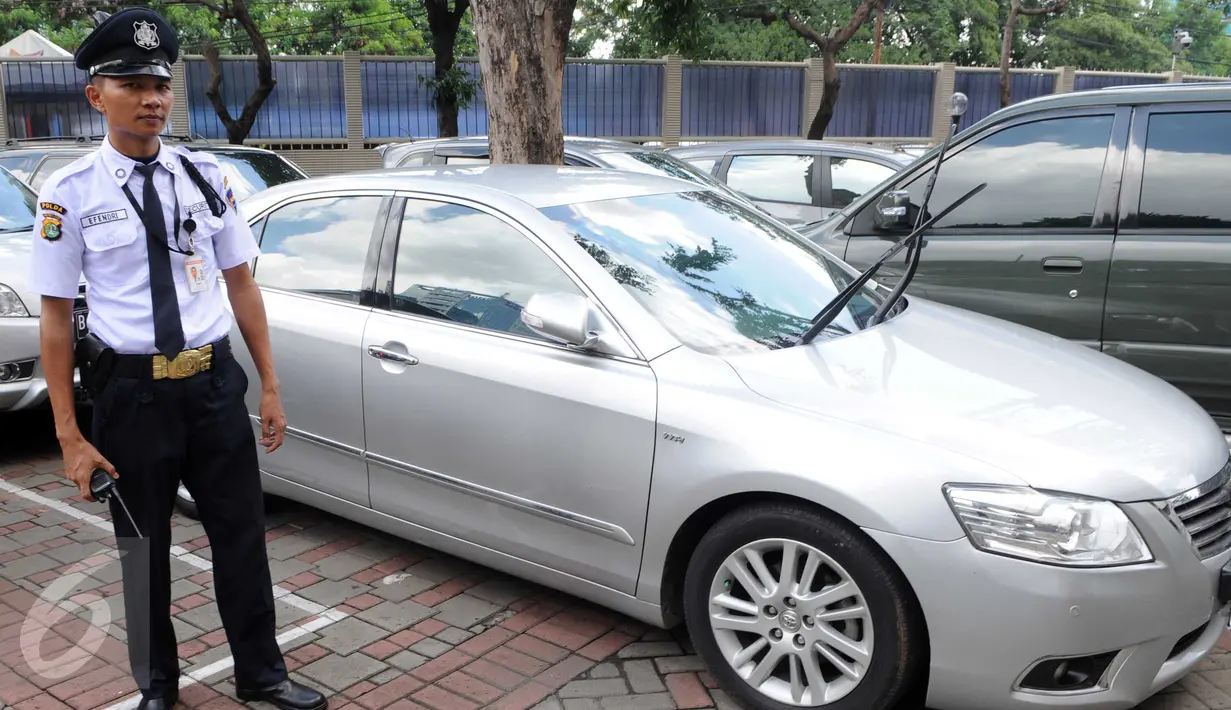 Petugas berdiri di dekat mobil Toyota Camry yang terparkir di halaman Gedung KPK, Jakarta, Senin (15/2). Mobil ini diamankan saat OTT terhadap Kepala Sub Direktorat Kasasi dan PK Perdata dan Khusus MA, Andri Tristianto Sutrisna (Liputan6.com/Helmi Afandi)